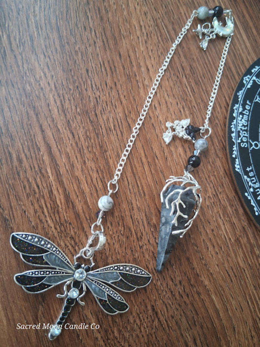 Larvikite moon pendulum with silver dragonfly charm and chain from Sacred Moon Candle Co altar tools