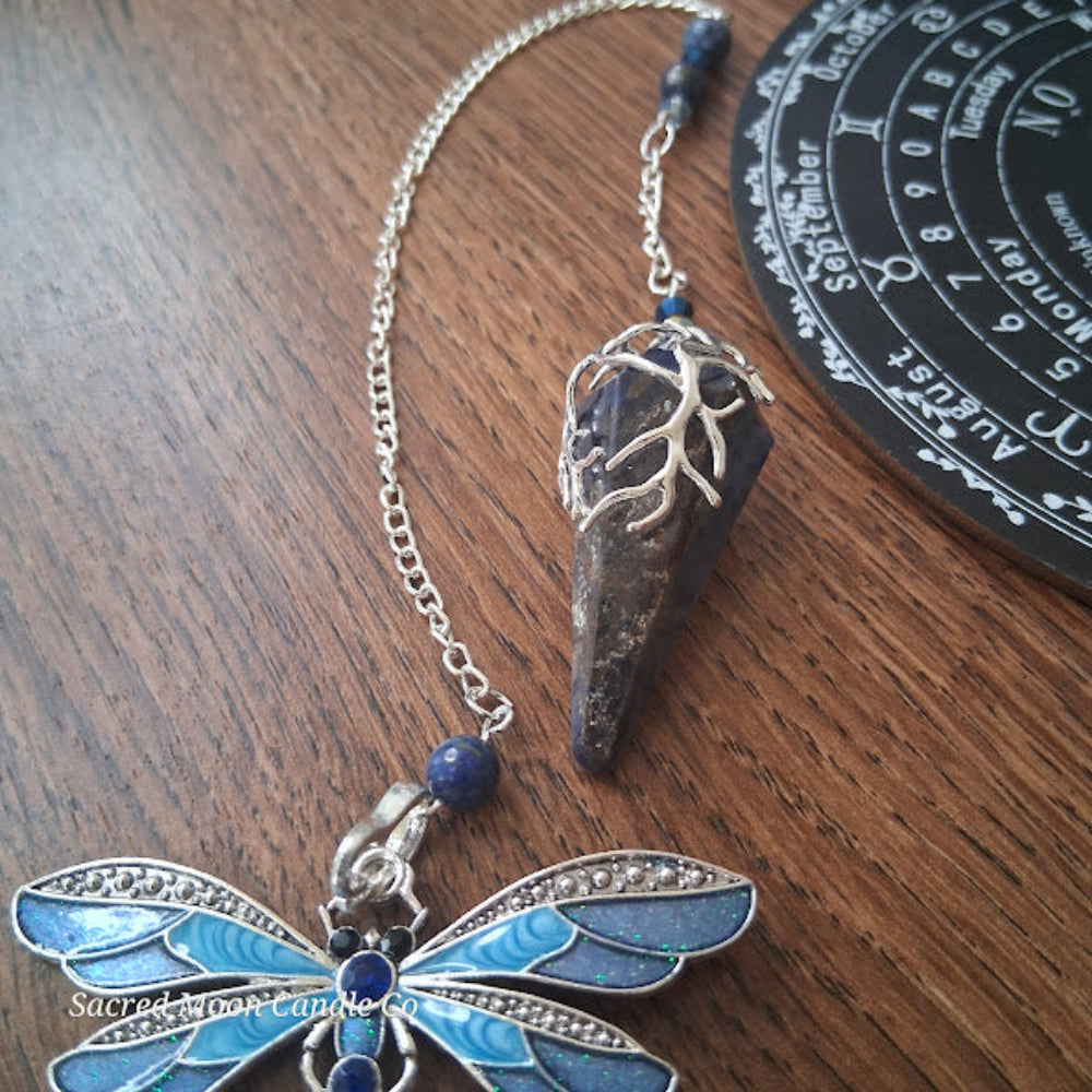 sodalite and lapis lazuli pendulum with silver chain and blue dragonfly charm on wooden surface