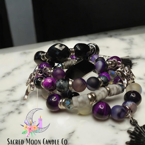 Spiritual protection beaded bracelets stack in purple and black tones by Sacred Moon Candle Co on marble surface