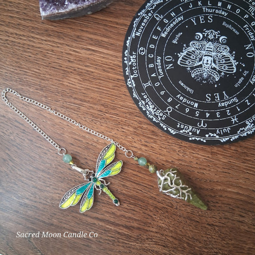 Unakite amazonite dragonfly pendulum with green gemstone and decorative silver detailing on wooden surface