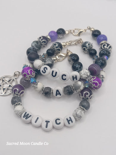 Witch bracelet stack from Sacred Moon Candle Co with purple and black beads and letter charms