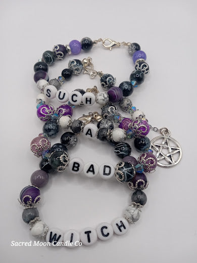 Sacred Moon Candle Co witch bracelet stack featuring purple, black, white beads and pentagram charm