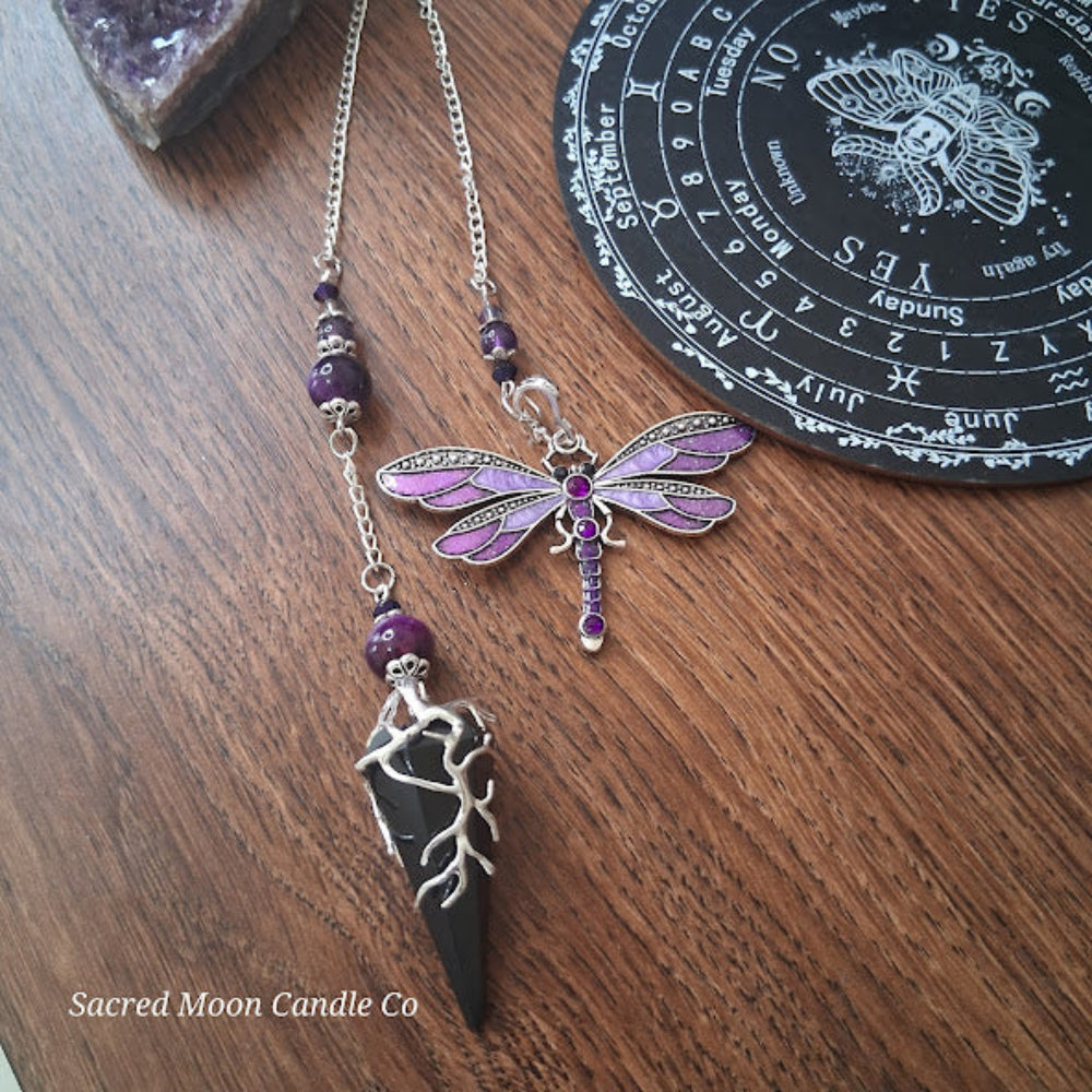 Black tourmaline Purple Tigers Eye Dragonfly Pendulum altar tool with purple bead accents on wood surface