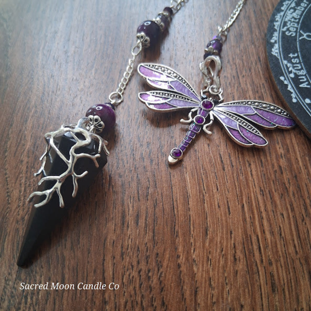 Black tourmaline Purple Tigers Eye Dragonfly Pendulum altar tool with silver detailing on wooden surface