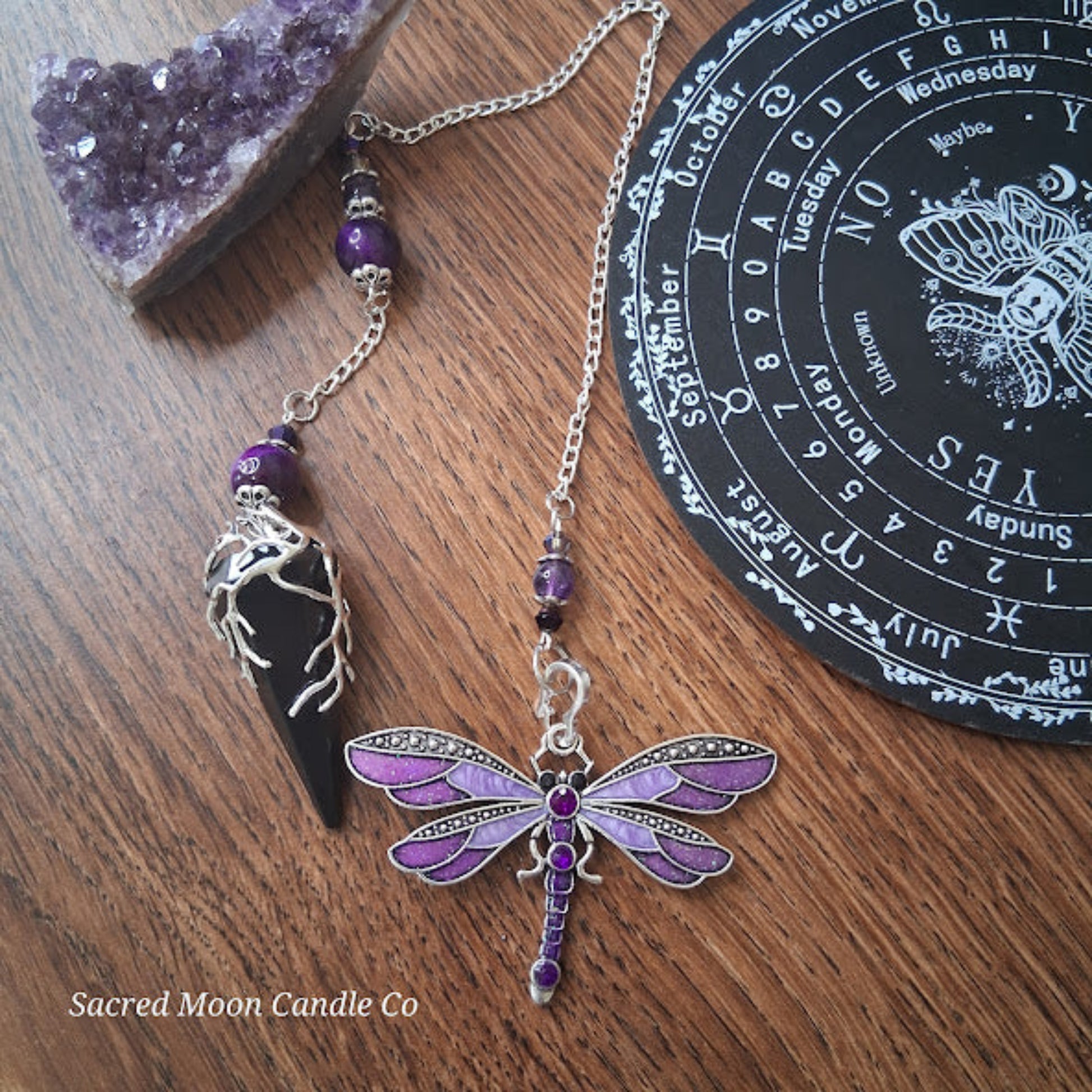 Black tourmaline Purple Tigers Eye Dragonfly Pendulum with silver chain and purple beads on wooden surface