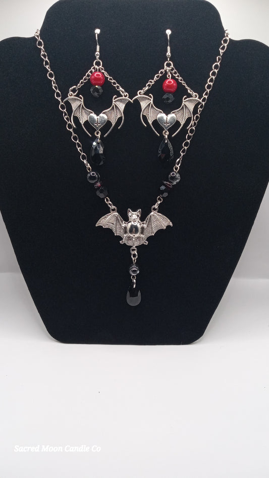 Sacred Moon Candle Co gothic bat jewelry set featuring silver bat earrings and matching necklace with black and red beads