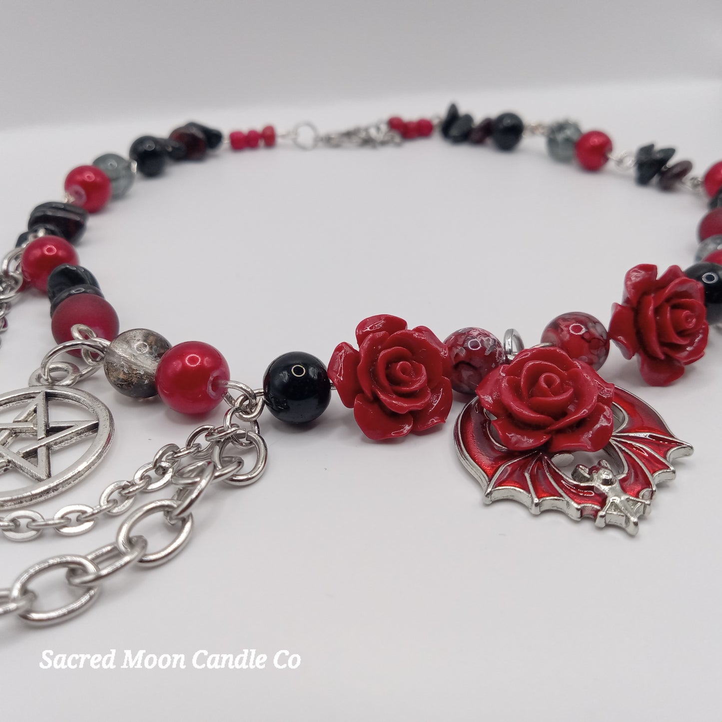 Handmade rose bat choker necklace with red rose beads, black and red accents, and silver chain from Sacred Moon Candle Co
