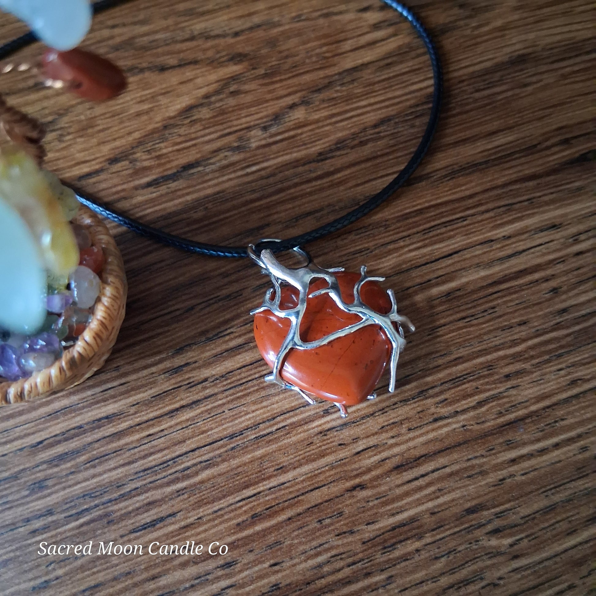 Red Jasper Tree Branch Wrapped Heart Stone Pendant  close up 4 Necklace by Sacred Moon Candle Co on wooden surface