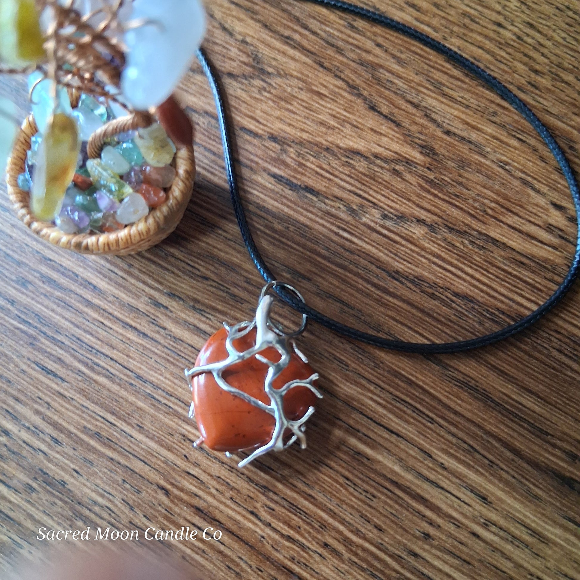 Red Jasper Tree Branch Wrapped Heart Stone Pendant Necklace by Sacred Moon Candle Co on wooden surface