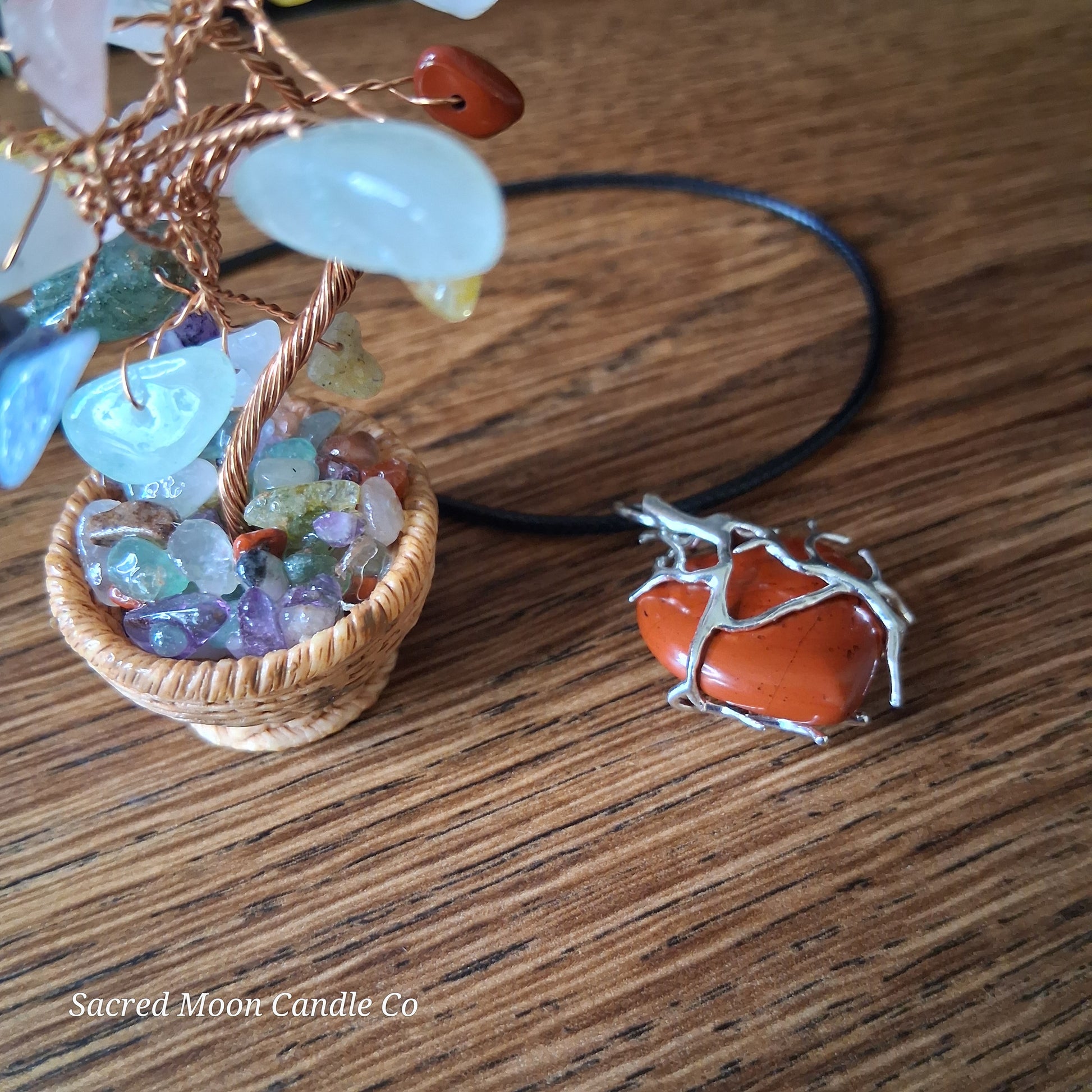Red Jasper Tree Branch Wrapped Heart Stone Pendant Necklace with silver wire design on wood surface