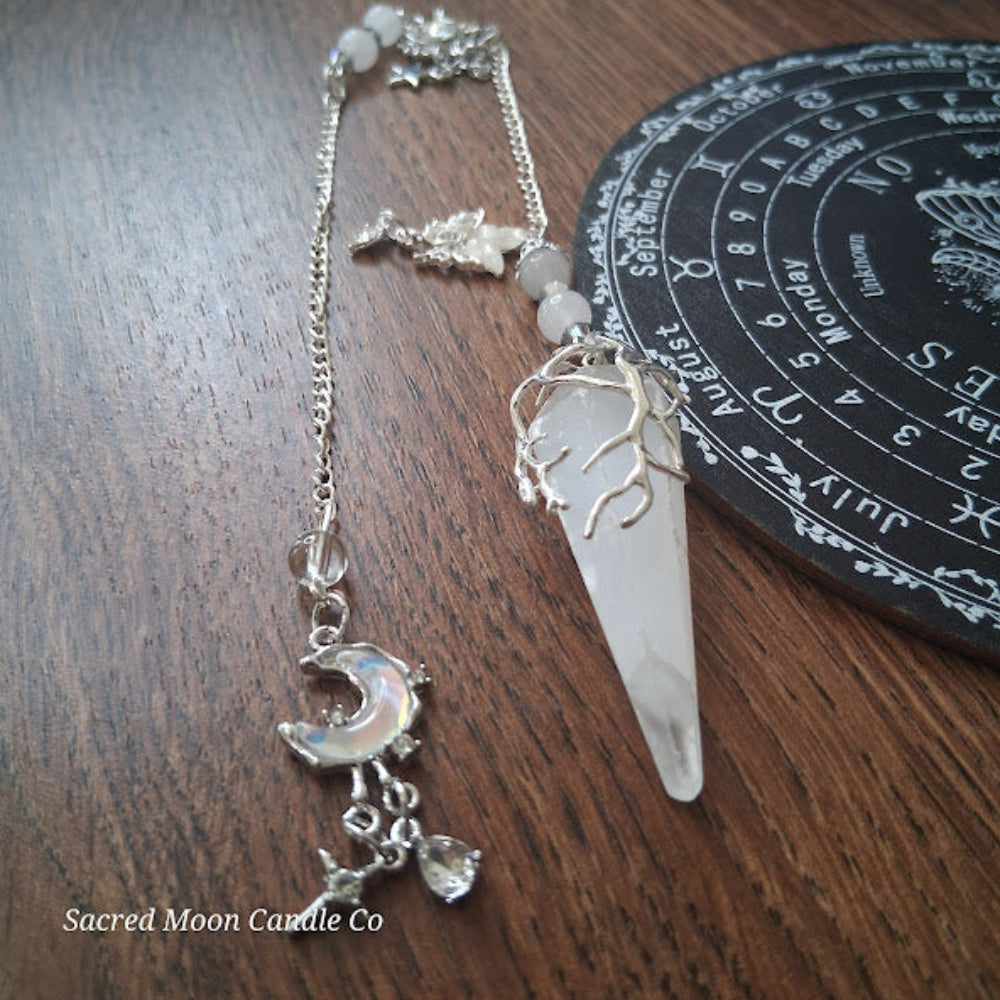 Selenite moon pendulum with silver chain and moon charm by Sacred Moon Candle Co on wooden surface