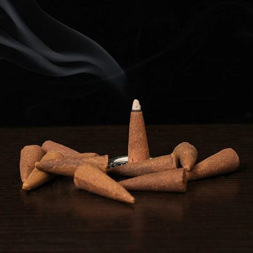 Burning safflower musk incense cones from Sacred Moon Candle Co arranged on dark surface with smoke
