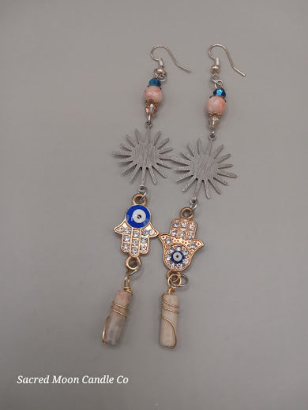 Sunburst Hamsa evil eye earrings by Sacred Moon Candle Co with silver sunburst and dangling charm