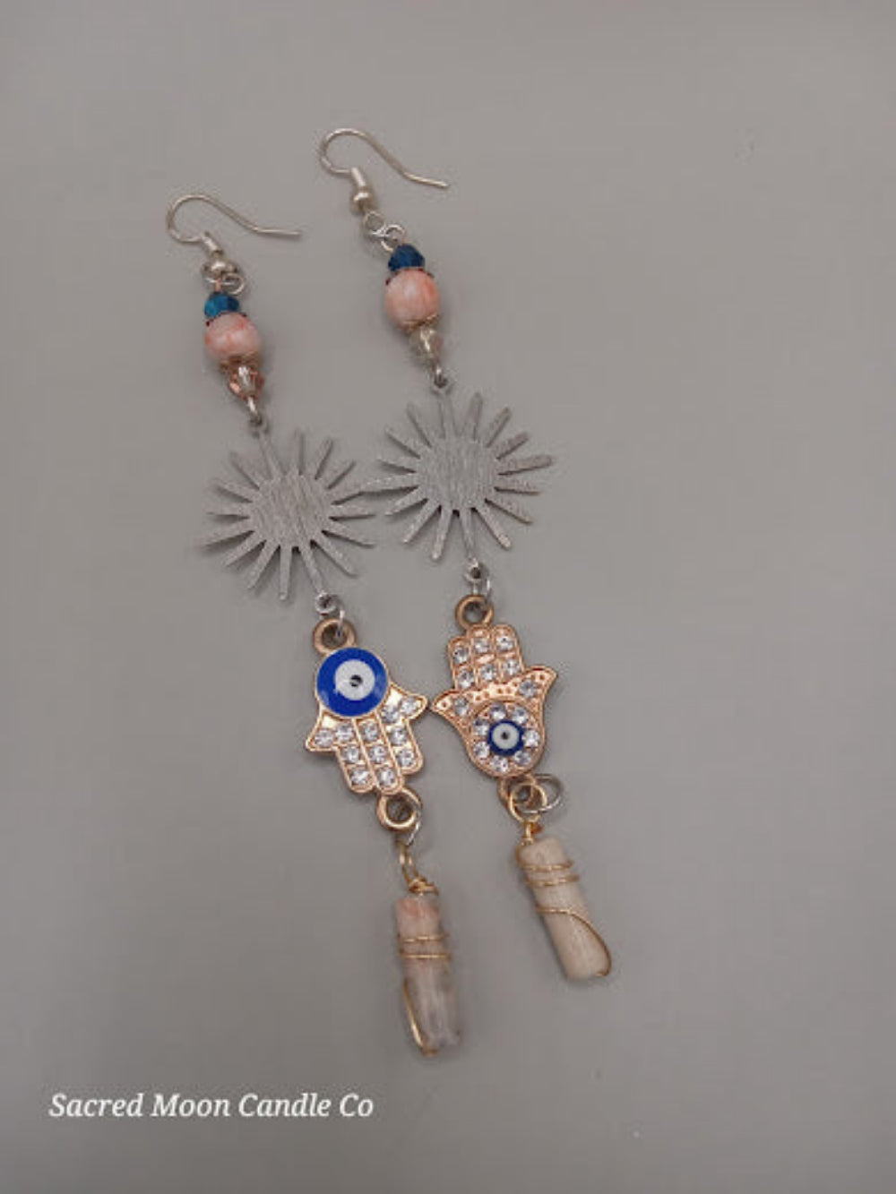 Sacred Moon Candle Co Sunburst Hamsa evil eye earrings with blue bead and crystal charm