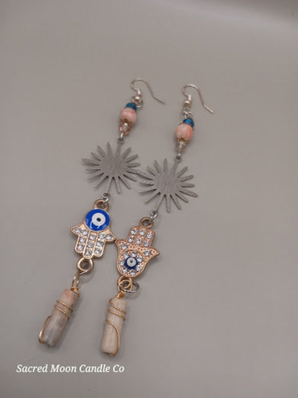 Sunburst Hamsa evil eye earrings by Sacred Moon Candle Co with silver sunburst, blue beads, and stone drops