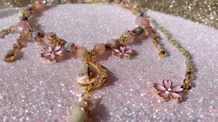 Sacred Moon Candle Co sakura blossom moon choker with pink flower charms and gold accents on glitter background