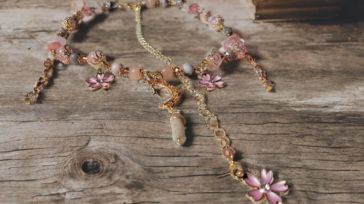 Sacred Moon Candle Co sakura blossom moon choker featuring pink flower charms and gold-tone chain on wooden background