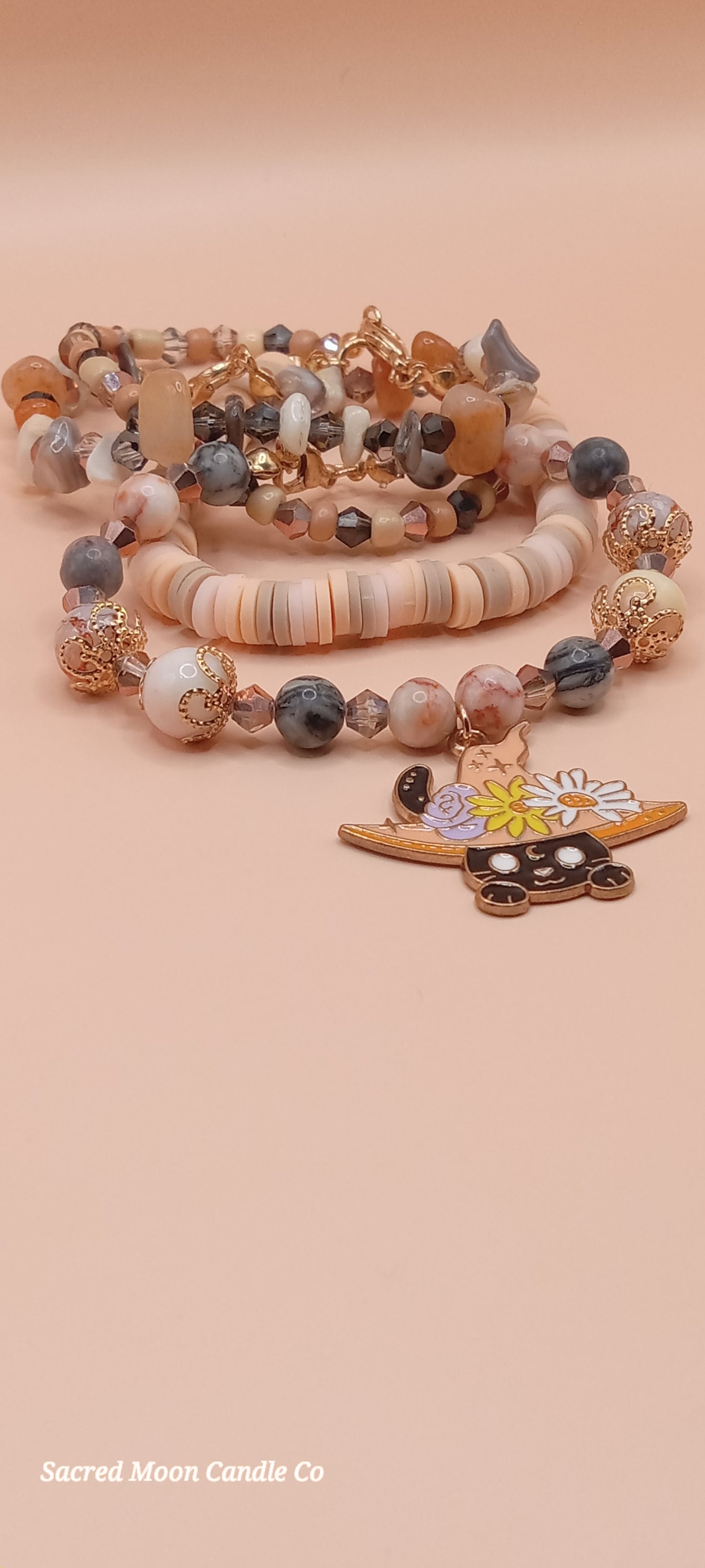 Sacred Moon Candle Co bracelet stacks featuring a witchy cat charm bracelet with neutral beads and detailed charms