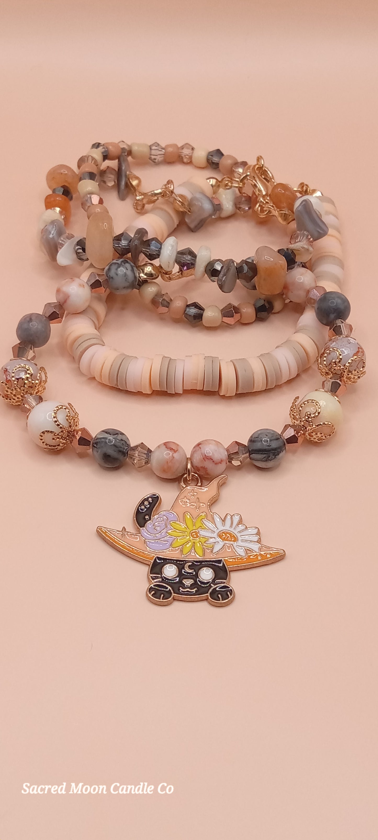 Sacred Moon Candle Co bracelet stacks featuring a witchy cat charm bracelet with earthy beads and a floral hat charm