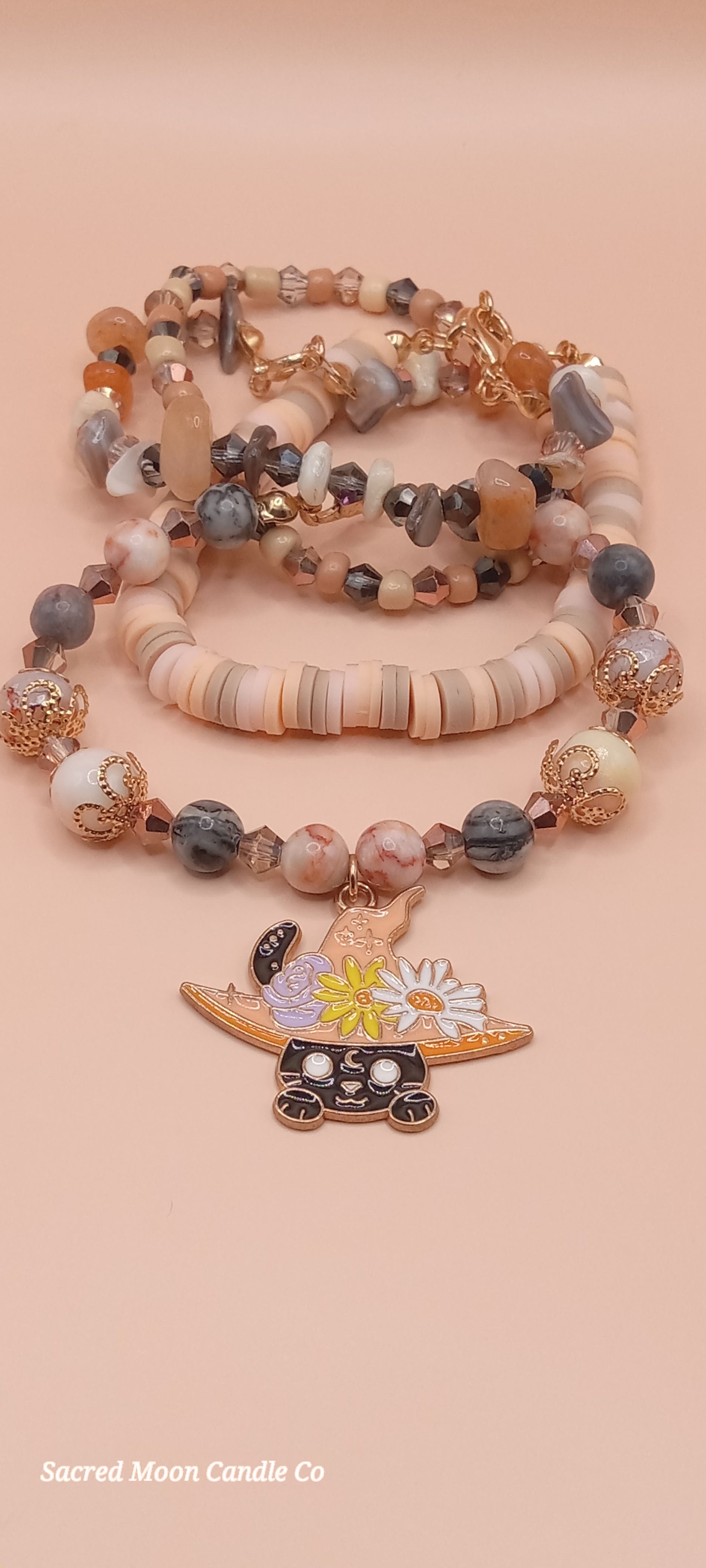 Sacred Moon Candle Co bracelet stacks featuring a witchy cat charm bracelet with earthy beads and a floral hat charm