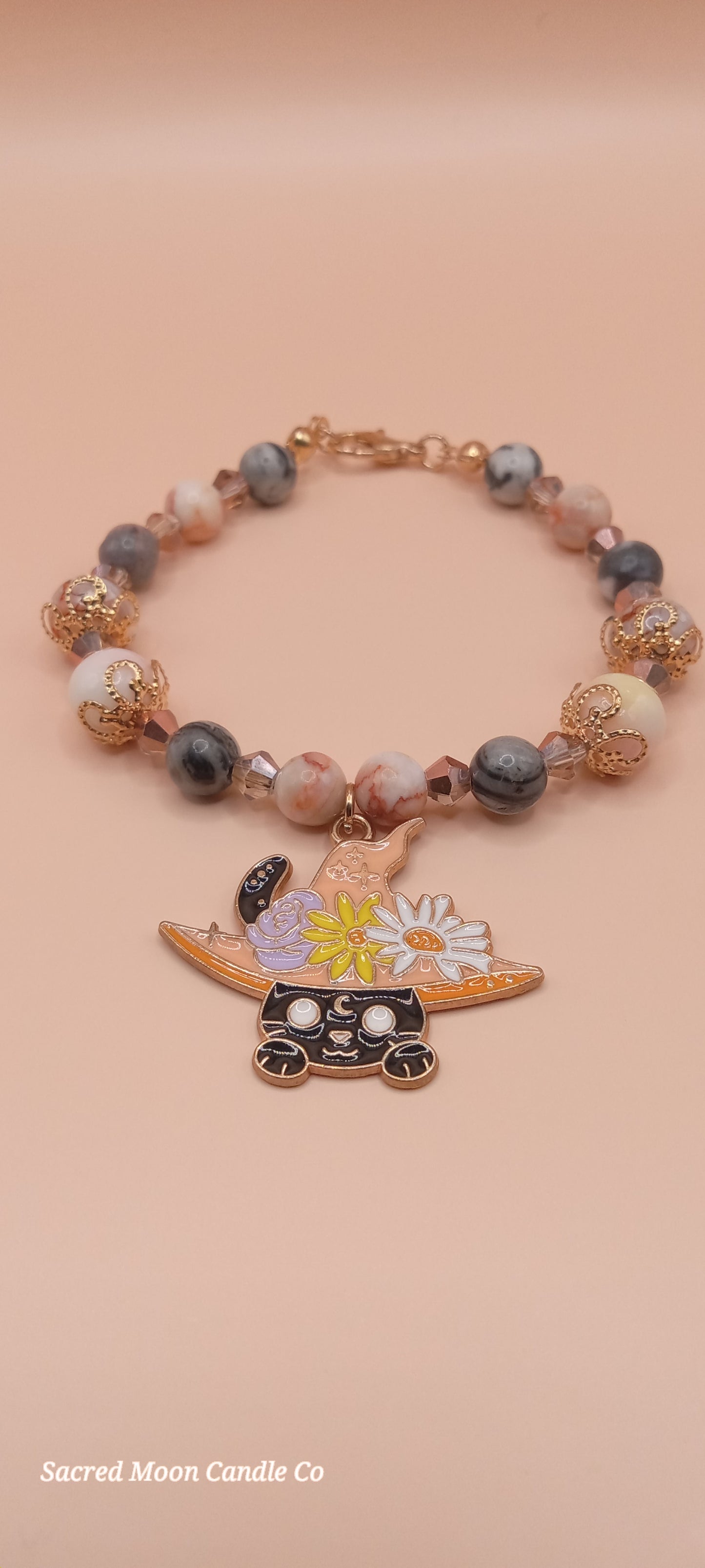 Sacred Moon Candle Co bracelet stack featuring a witchy cat charm bracelet with beads and floral details