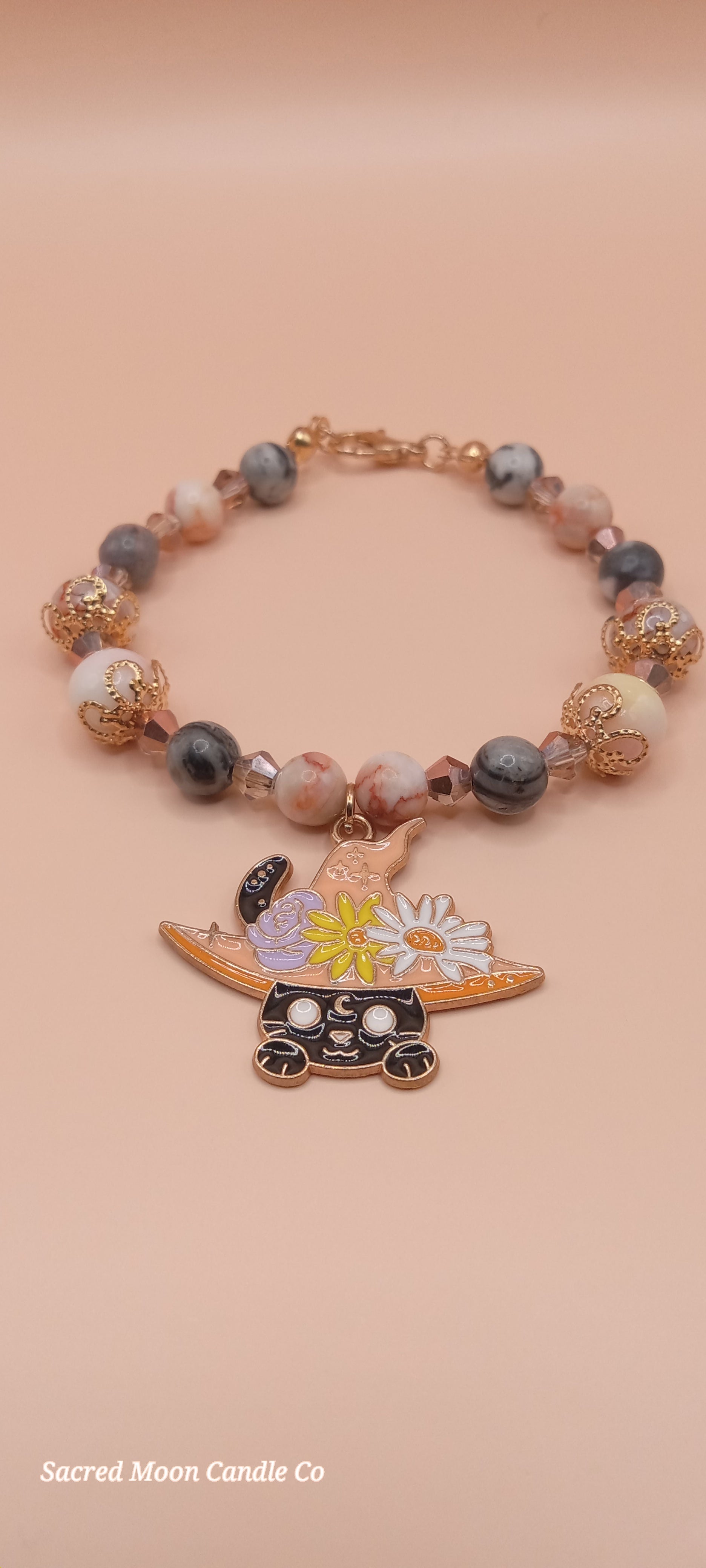 Sacred Moon Candle Co bracelet stack featuring a witchy cat charm bracelet with beads and floral details