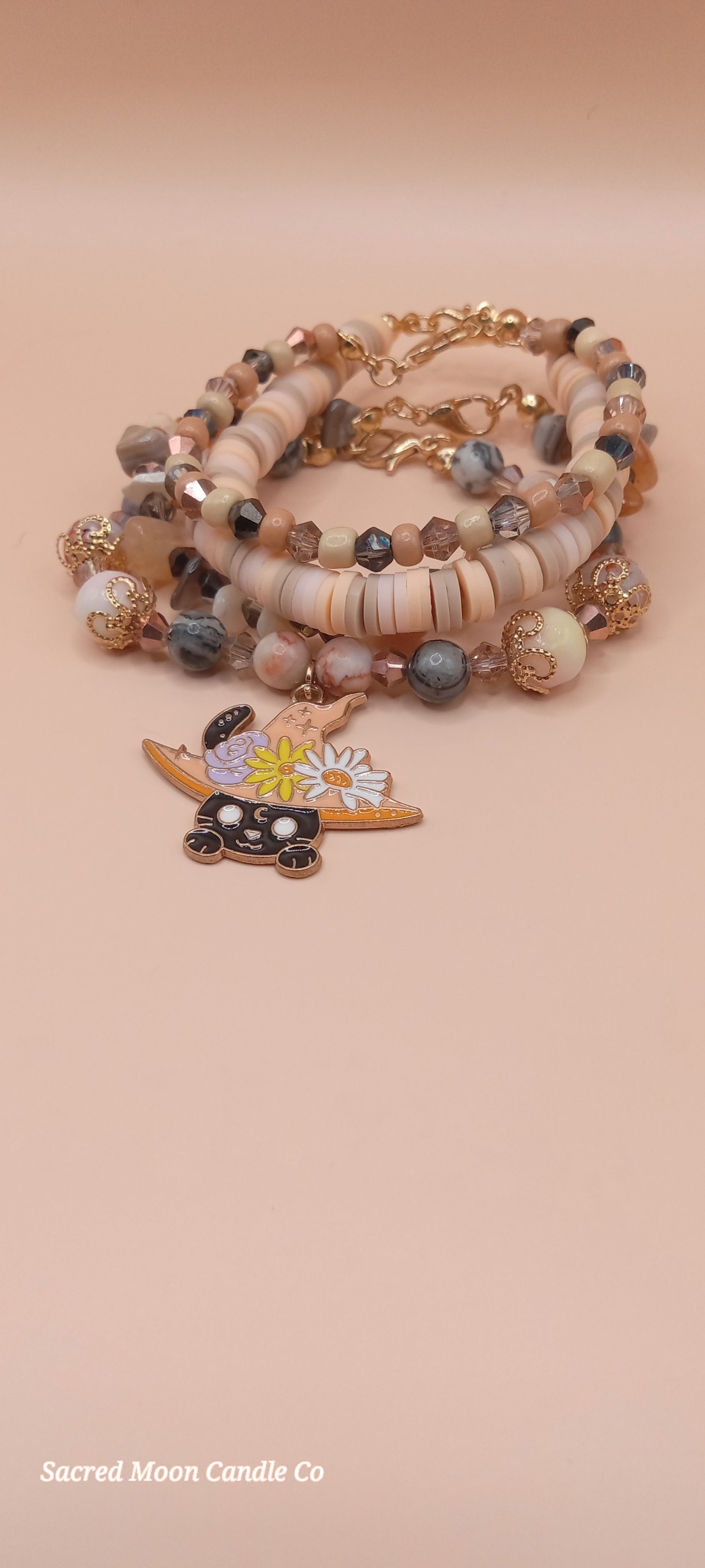 Sacred Moon Candle Co bracelet stacks featuring a witchy cat charm bracelet with neutral beads and gold accents