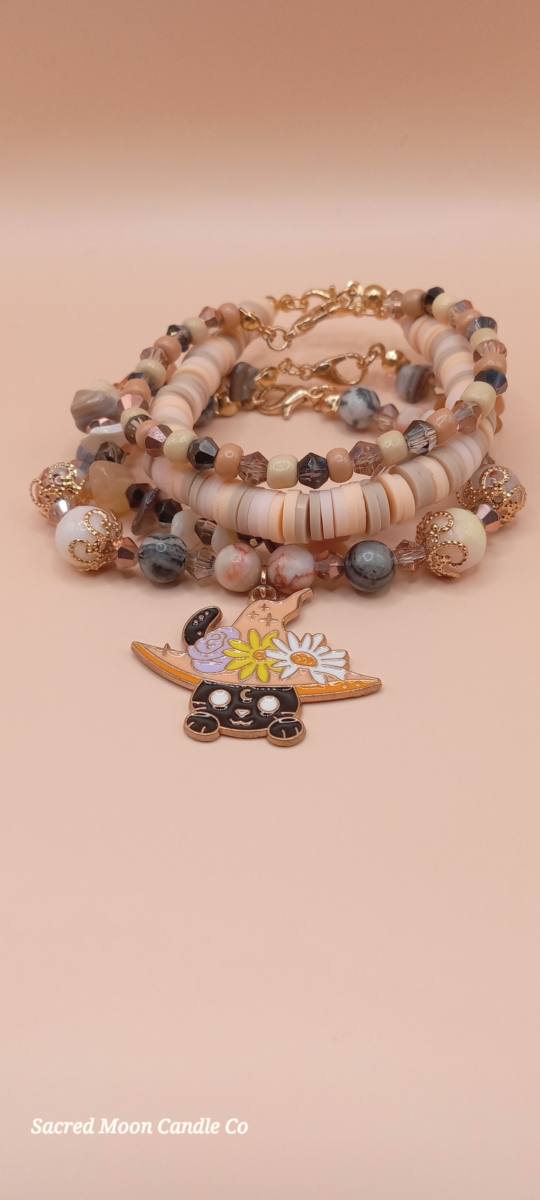Sacred Moon Candle Co bracelet stacks featuring a witchy cat charm bracelet with neutral and earthy beads