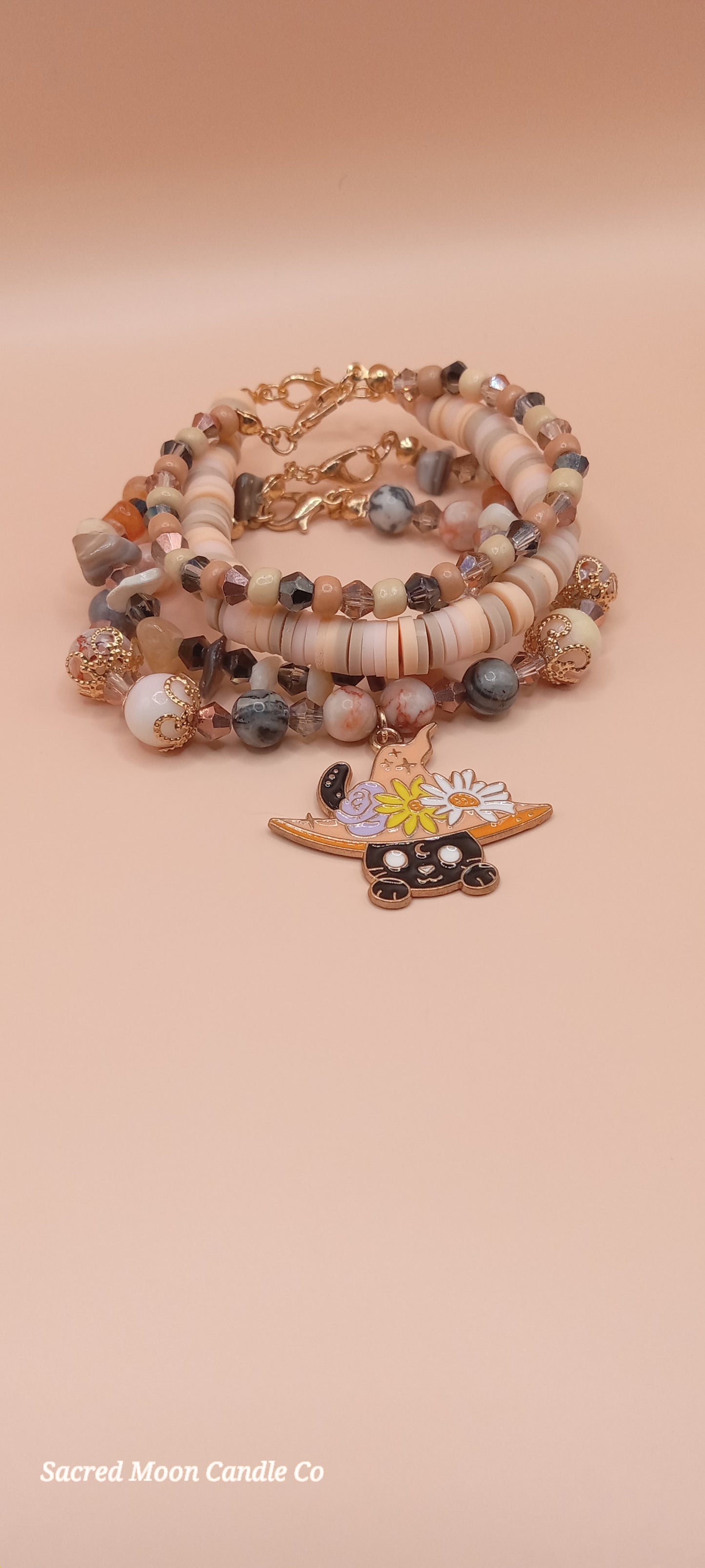 Sacred Moon Candle Co bracelet stacks featuring a witchy cat charm bracelet with natural stone beads and floral details