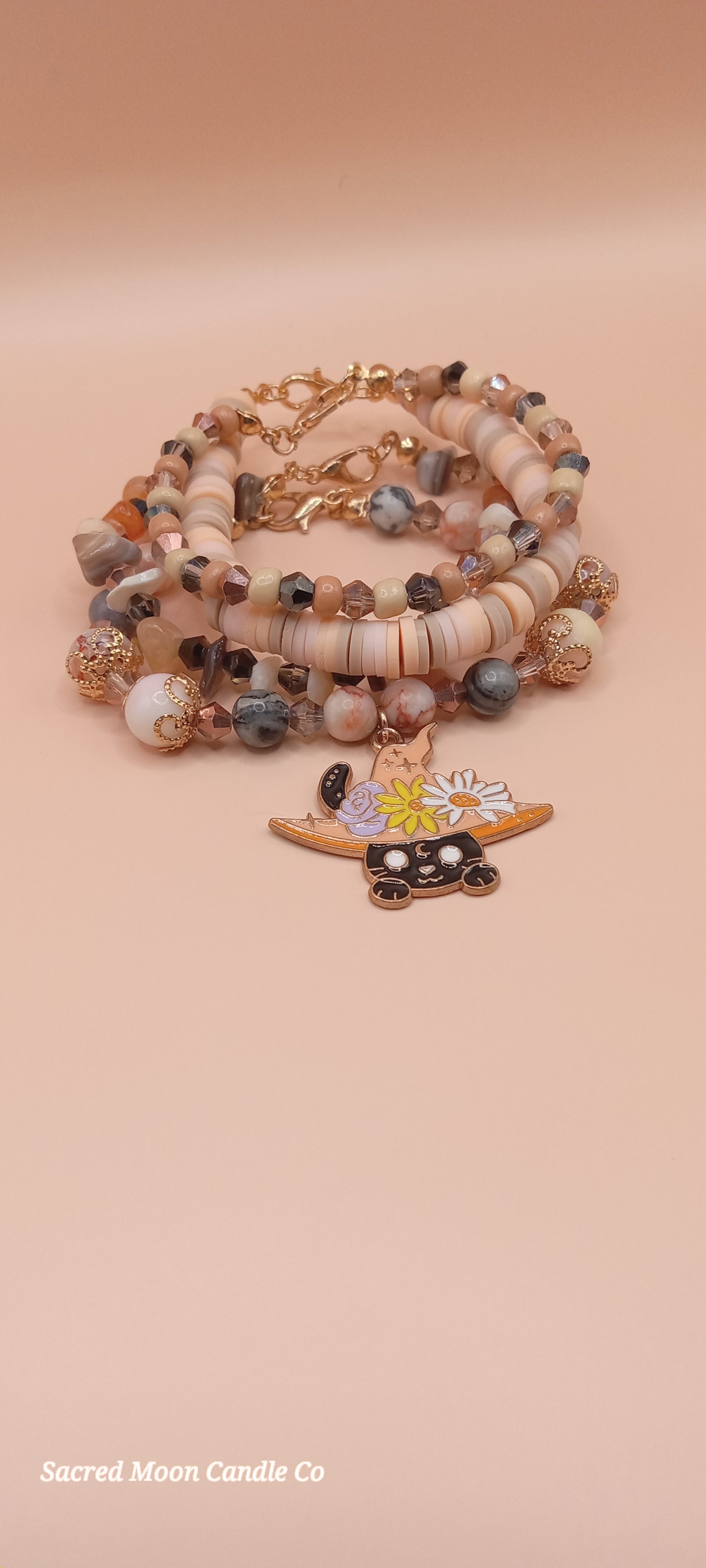 Sacred Moon Candle Co bracelet stacks featuring a witchy cat charm bracelet with natural stone beads and floral details